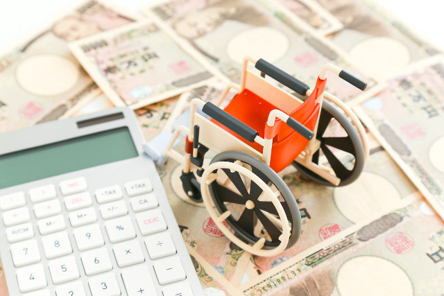 お金と車いすのミニチュアと電卓